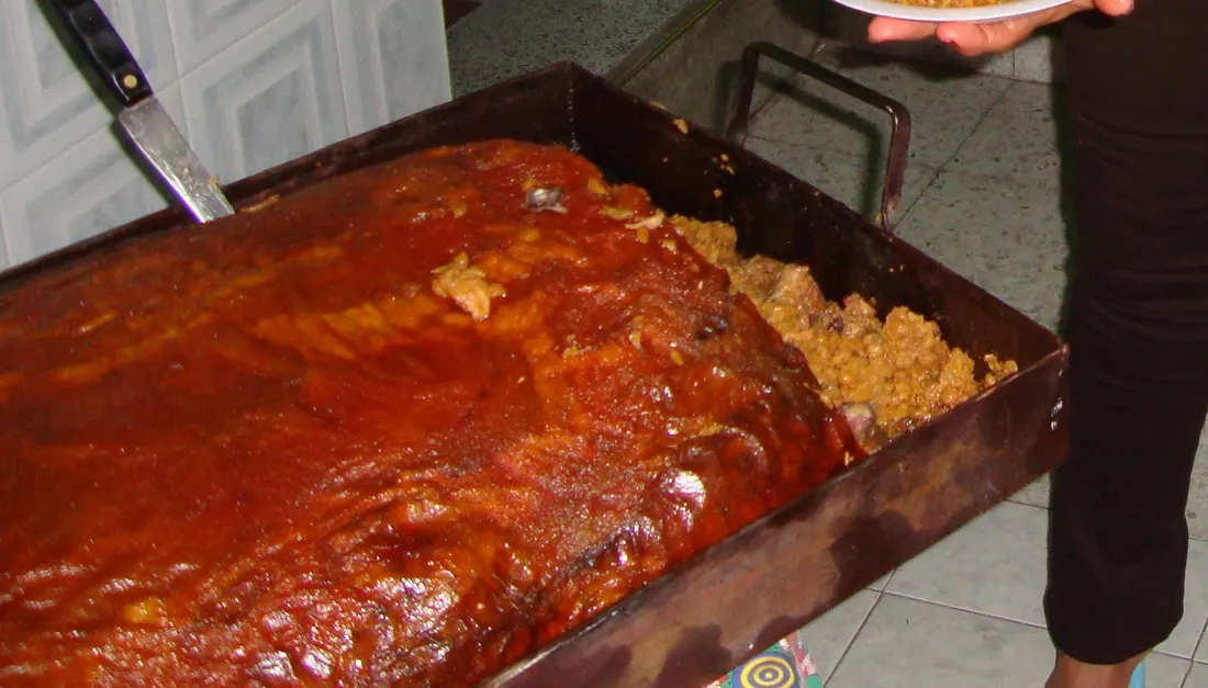 Lechona horneada en su bandeja, mostrando el cuero crocante y el relleno de arroz, arveja y carne de cerdo