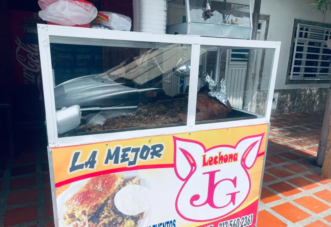 Puesto de Lechona JG en Zarzal, con el letrero de la marca y la lechona lista en su vitrina